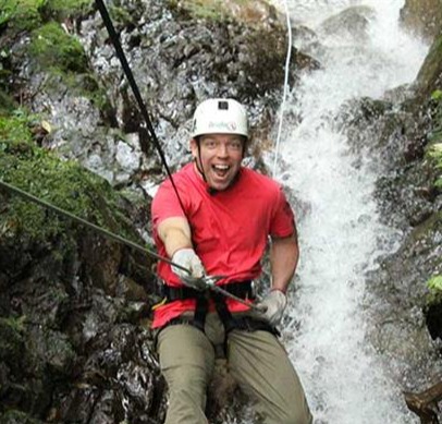 James, Profile weight loss member, scaling the side of a cliff with a stream underneath.