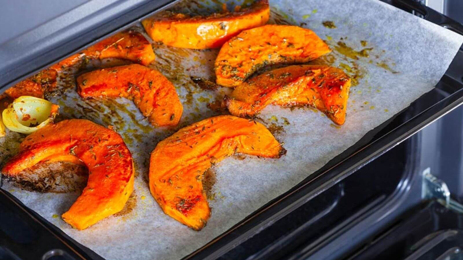 roasted acorn squash topped with olive oil and spices on a baking sheet lined with parchment paper