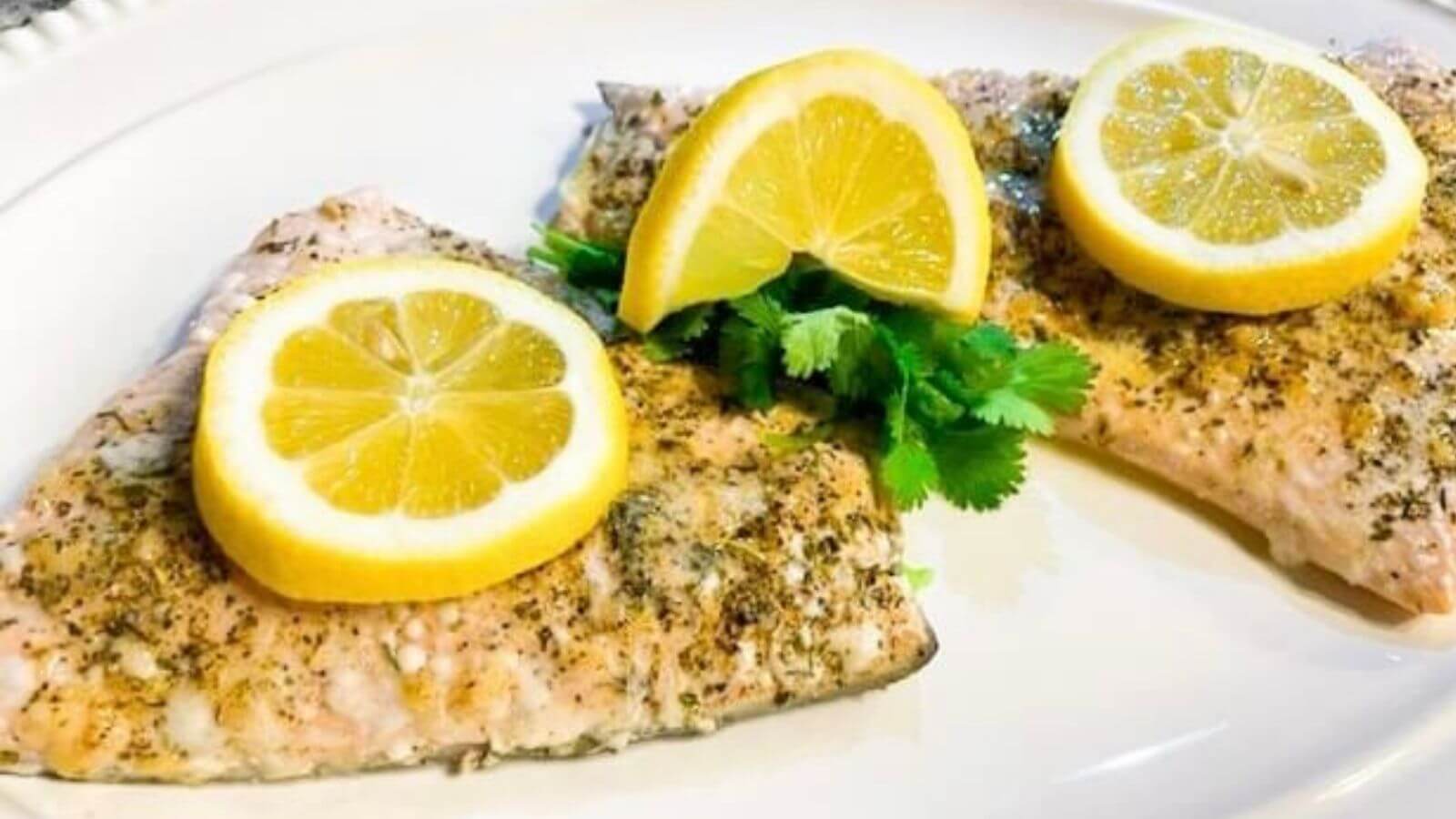 seasoned salmon topped with sliced lemons and parsley 