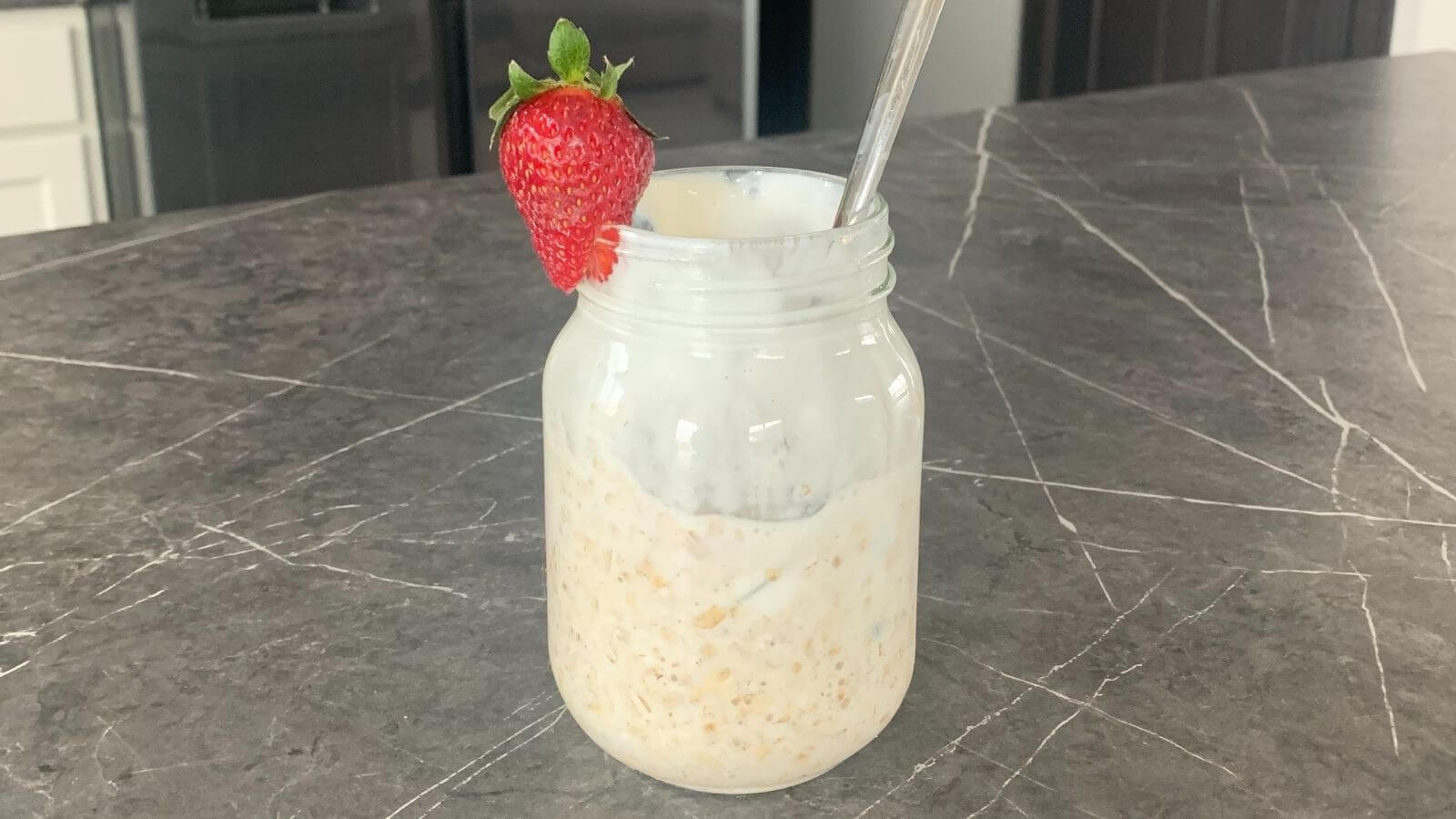 mason jar filled with overnight oats, garnished with a strawberry