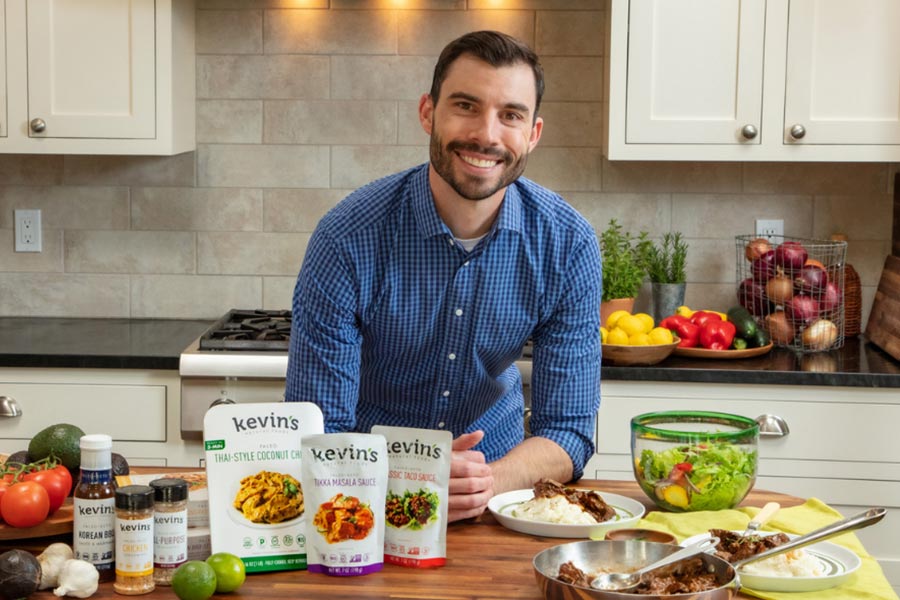 Man in a kitchen with Kevin's Natural Foods products