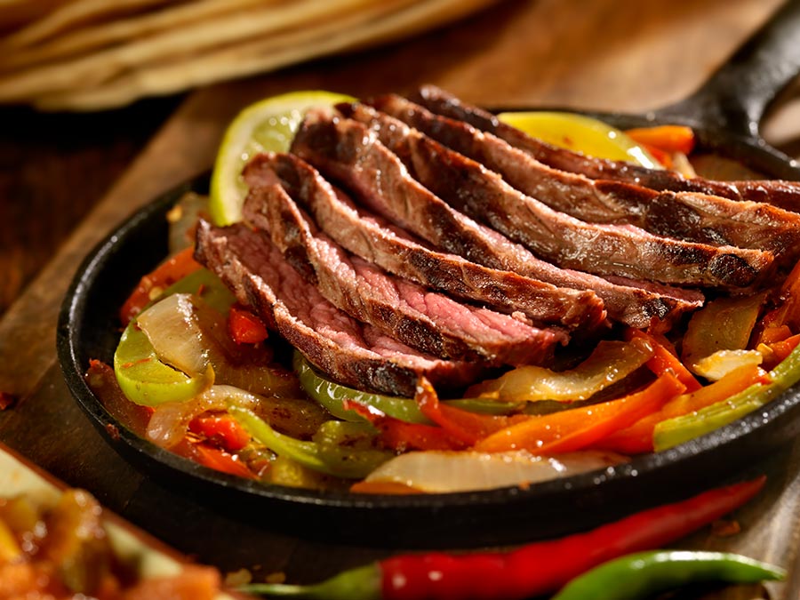 Steak fajita meat atop a bed of sliced bell peppers